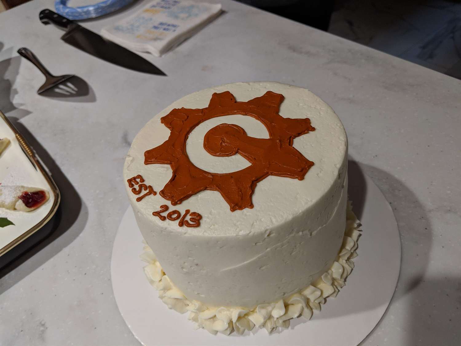 A white cake decorated with the orange Cognito Forms gear logo
