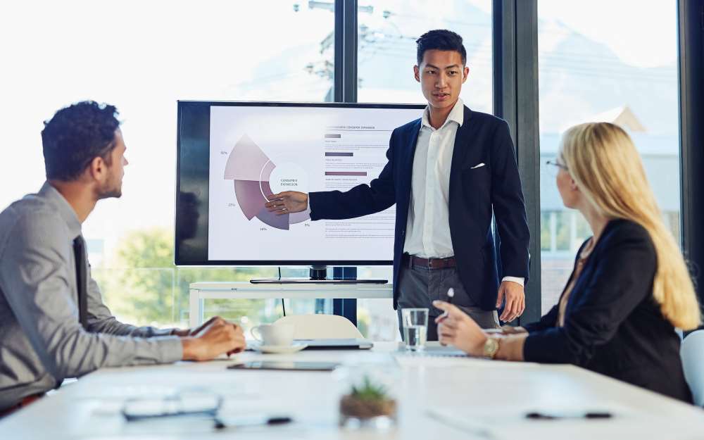 man standing and presenting quantitative data to team