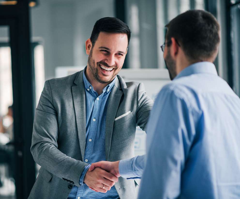 smiling business man in suit shaking hand with client