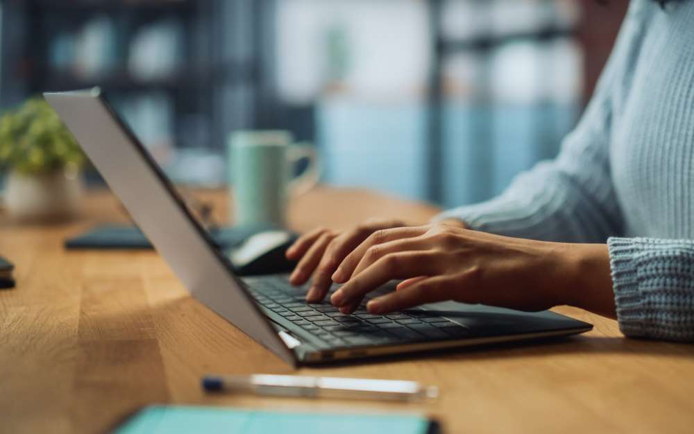 woman typing on a laptop accessing a client portal