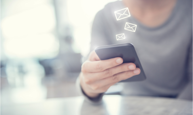 Person holding phone with email graphic coming from it.