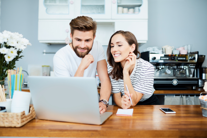 A woman and man looking at their computer together in a cafe.