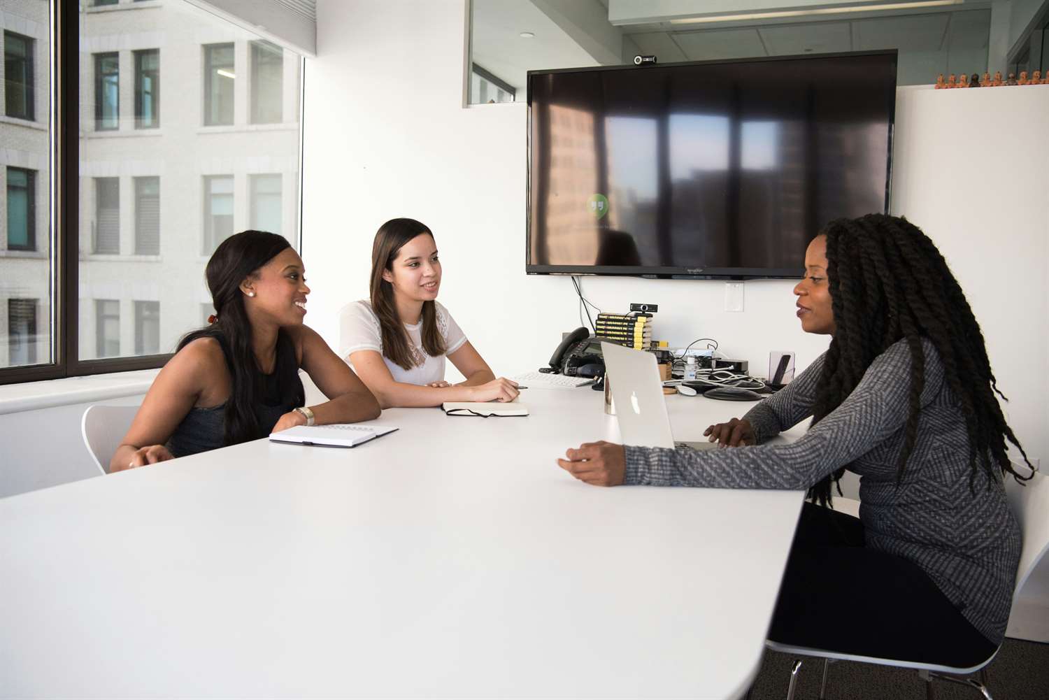 three women having a meeting at a table in an office