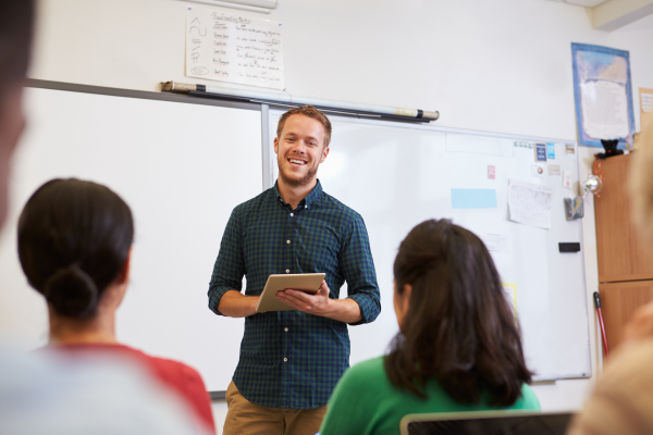 Teacher holding a tablet teaching students.