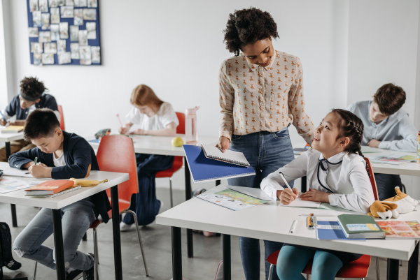 Teacher looking at student while helping her with work.