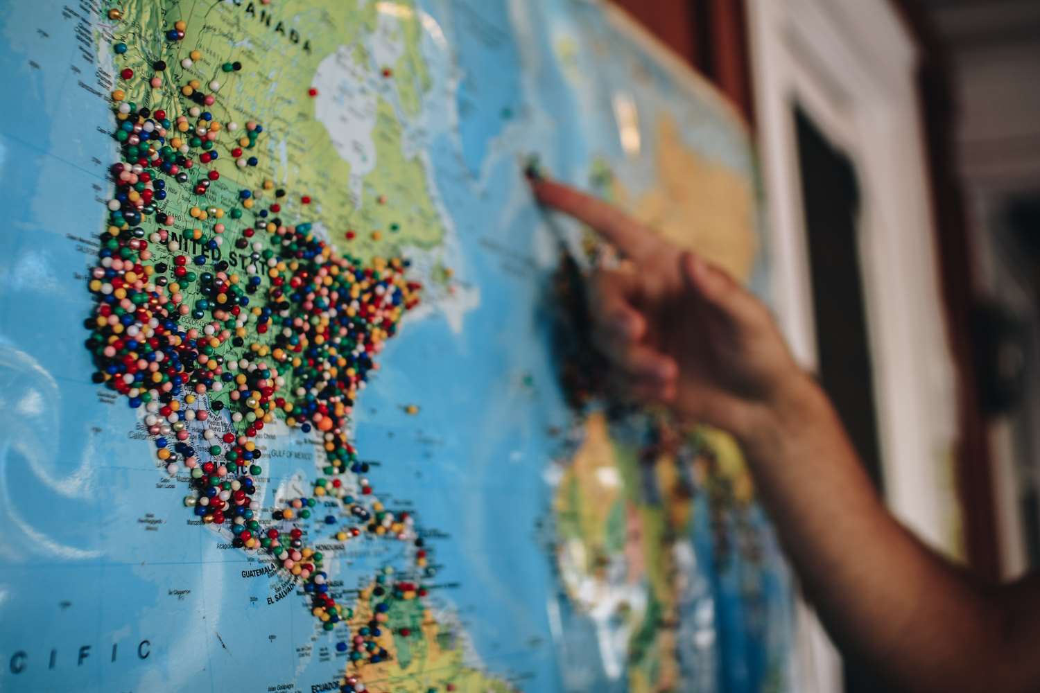 Person pointing to a map with pins in different areas.