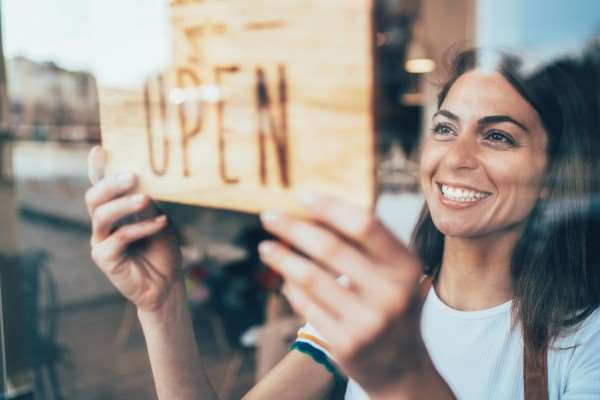 Small business owner with open sign.