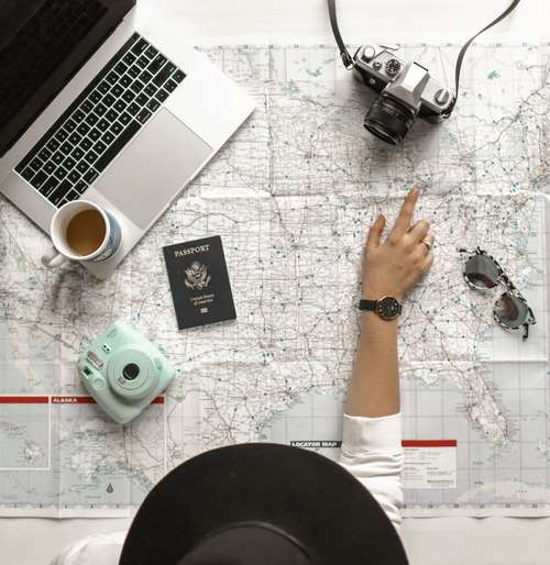 Woman pointing at a map with her passport and cameras planning to travel.