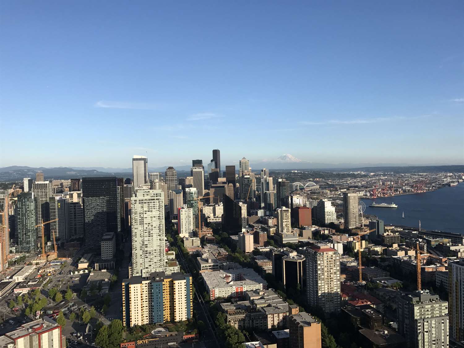 Aerial view of Seattle cityscape with tall skyscrapers and a waterfront in the distance.